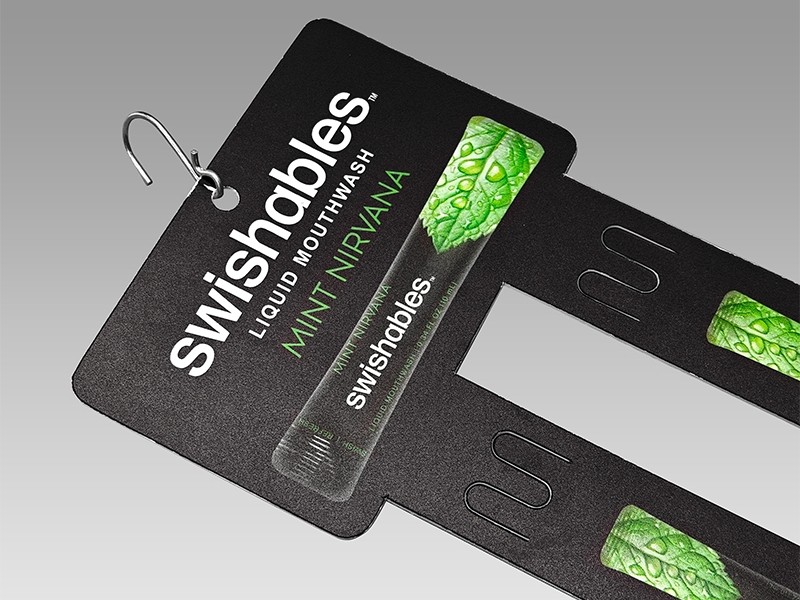 Header card and first slot: the euro hole sits on the M-shaped tongue, the body hangs in front of the printed face — hole, artwork and wordmark all readable at once.