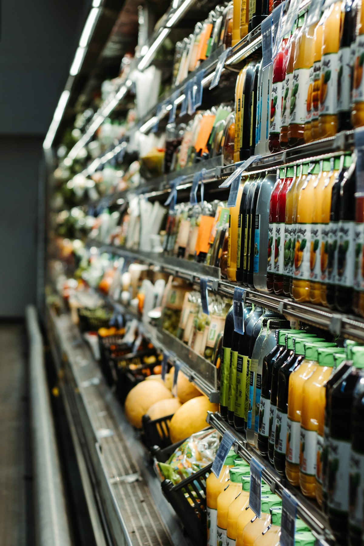 Chilled beverage cabinet filled with cans and bottles, the typical installation environment for a gravity roller shelf system