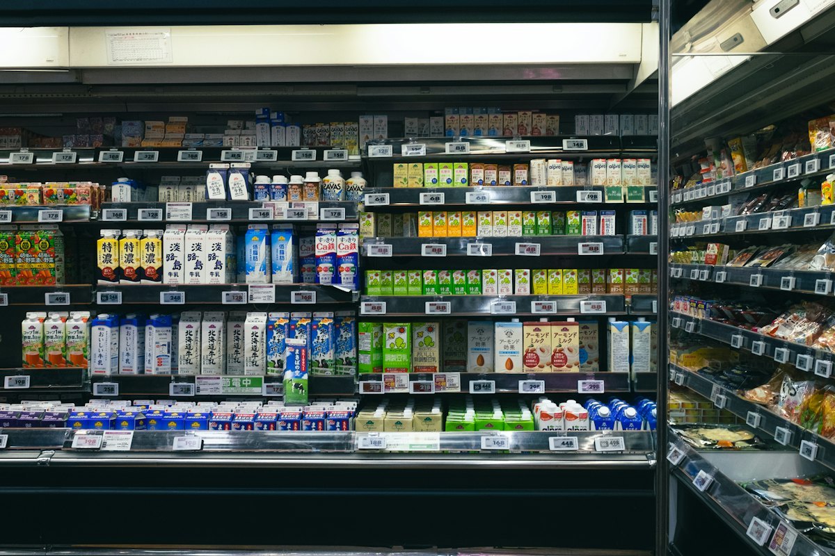 Convenience store drink cooler with cans and cartons arranged in tight, evenly spaced lanes