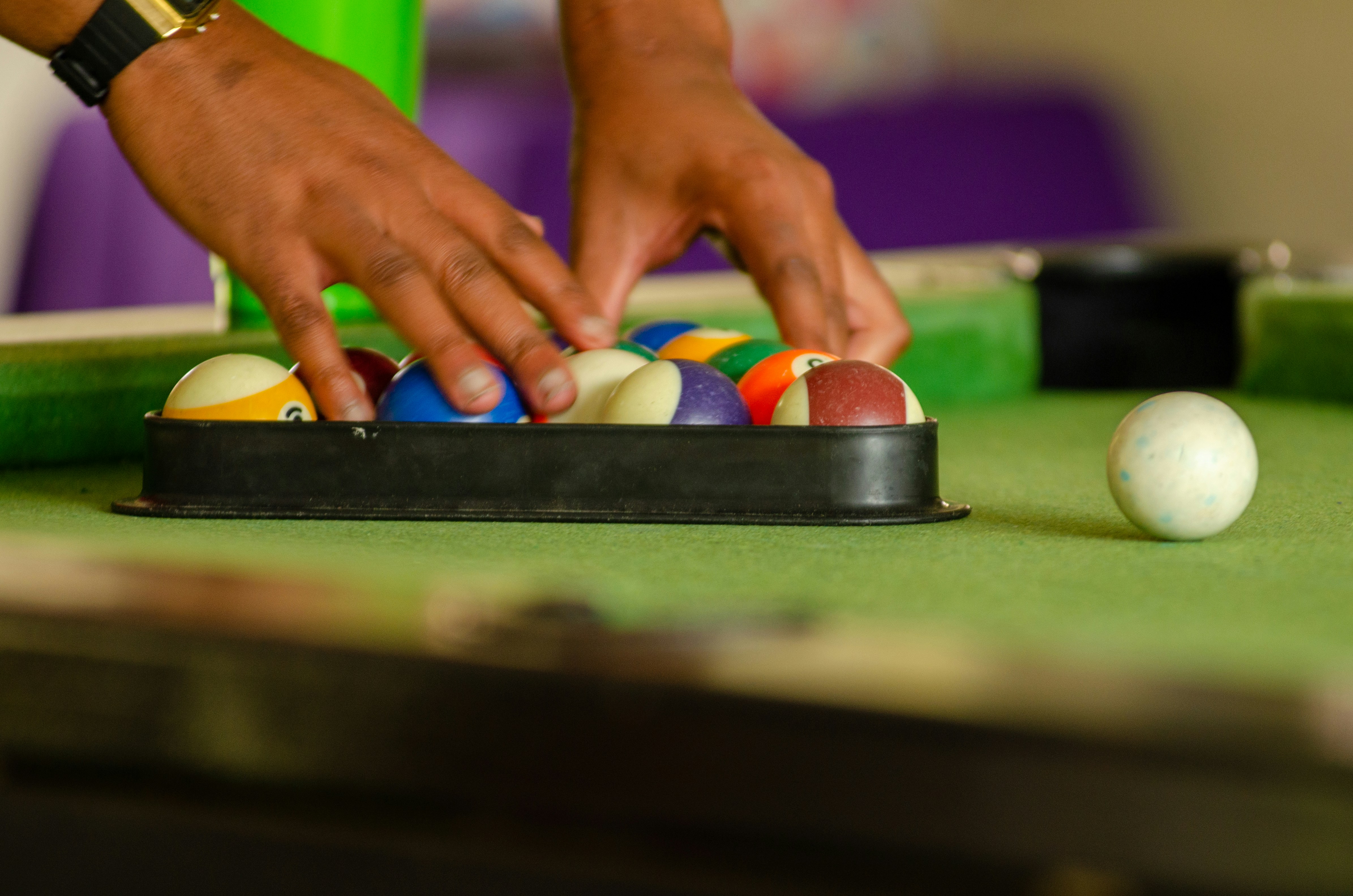 A child's hands threading colorful beads onto a green pipe cleaner.