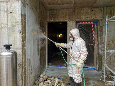 Worker spray-applying water-based low-VOC FEVE fluorocarbon topcoat onto a large concrete panel