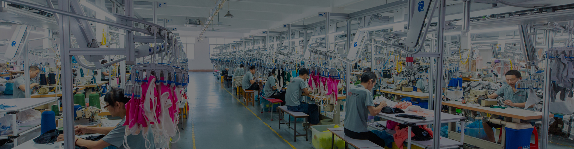 Wide view of a large-scale premium activewear manufacturing factory floor in full operation, showing busy sewing lines for bulk orders.