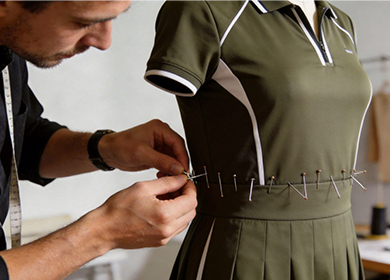 Fashion designer pinning fit sample on mannequin to adjust sizing for activewear production