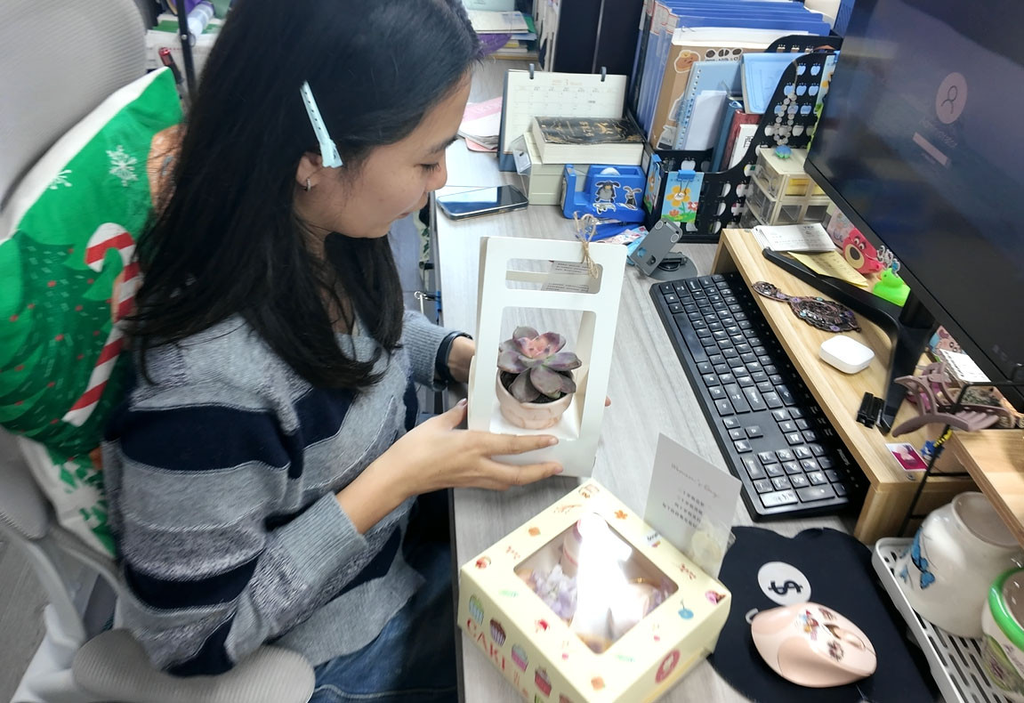 A female team member at Call The STYLE admiring her Women's Day succulent plant gift in the office.