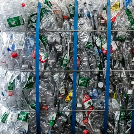 Bale of compressed post-consumer plastic bottles sourced for recycled activewear materials.