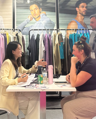 Sportswear manufacturing expert explaining custom fabrics and OEM services to a buyer at US Textile Show 2024.