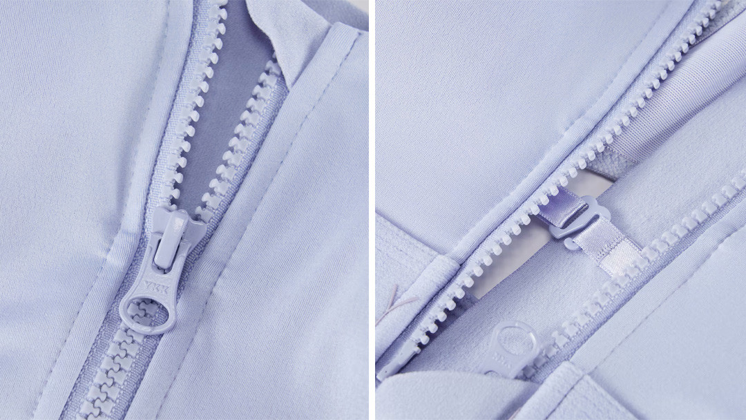 Macro shot of a YKK auto-lock zipper and internal construction details on a light blue high-performance activewear garment