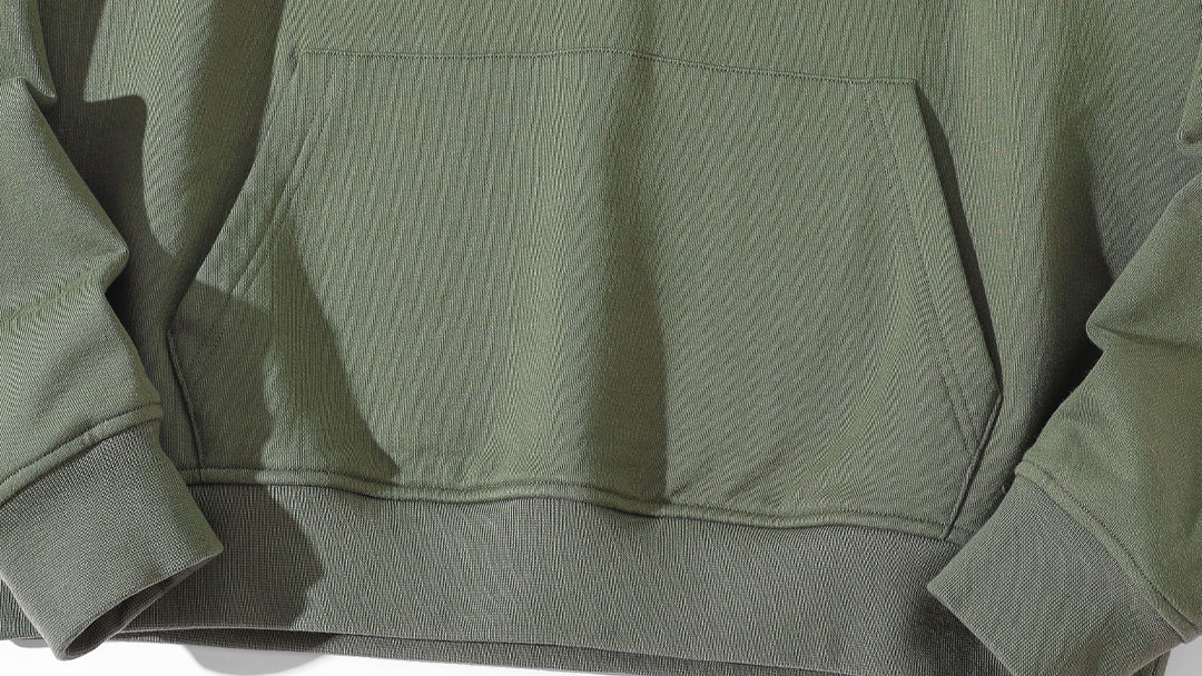 Olive green hoodie showing double-needle topstitching on kangaroo pocket and bottom hem