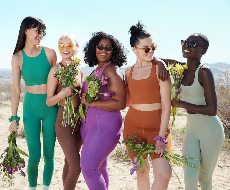 Diverse models showcasing an inclusive custom activewear collection featuring plus-size high-waisted leggings and sports bras in vibrant colors.