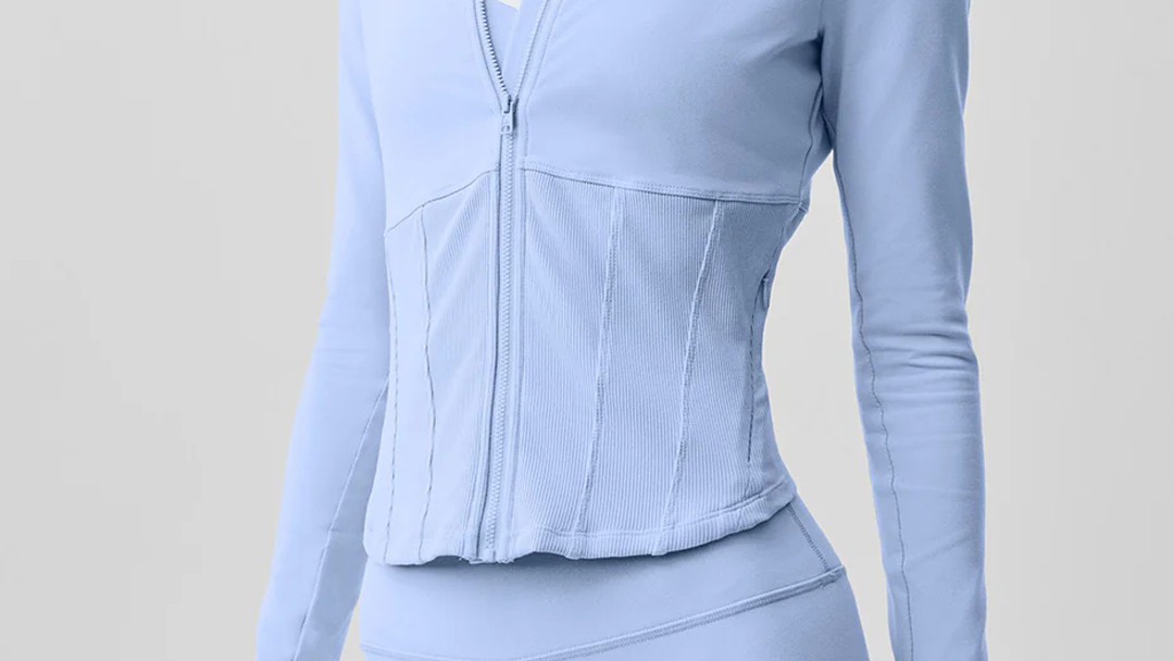 Light blue form-fitting active jacket showing vertical contour seams and an invisible pocket zipper