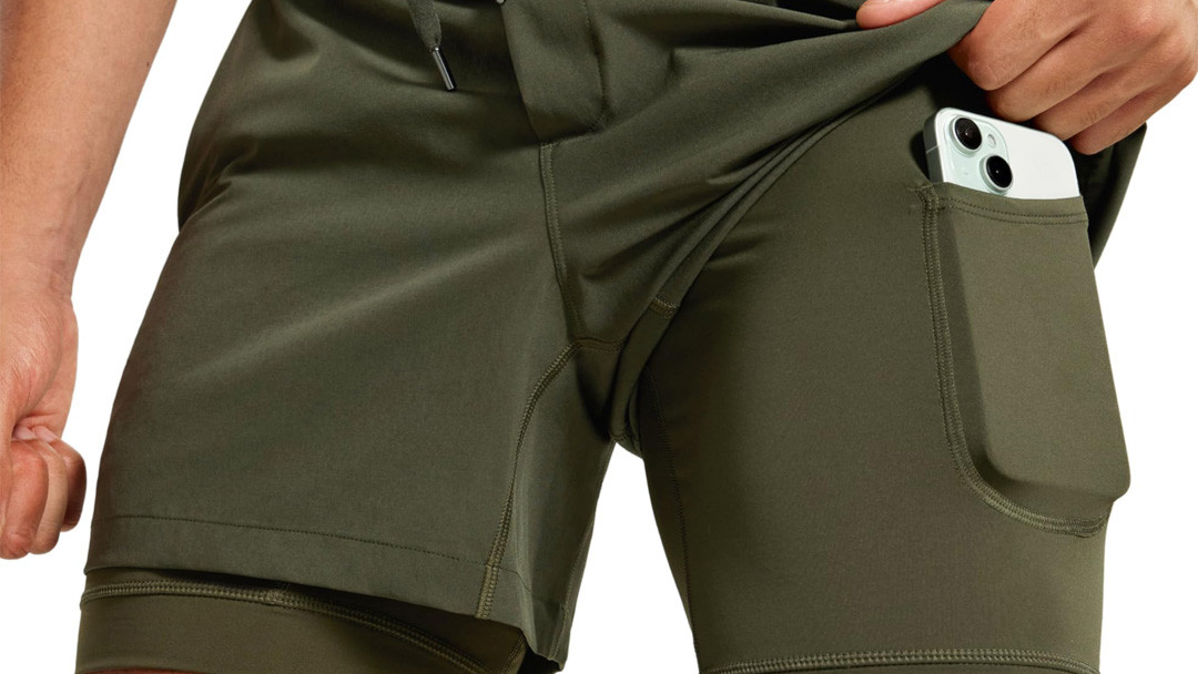 Men's 2-in-1 training short with outer shell lifted to reveal a compression phone pocket on the inner liner