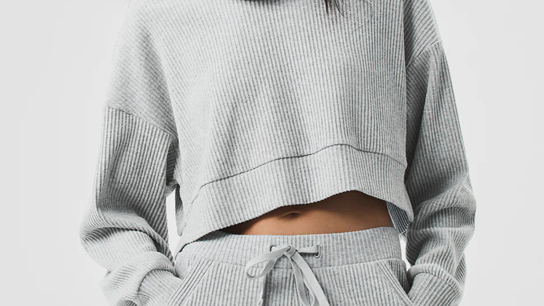 Close-up of a perfectly flat coverstitched hem on a soft gray cropped ribbed knit pullover.