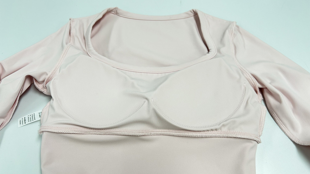 Inside construction of long-sleeve sports top showing built-in shelf bra and pad pockets