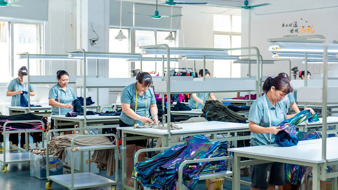 Ethical activewear manufacturing facility showing skilled operators sewing sustainable yoga wear in a clean well-lit factory