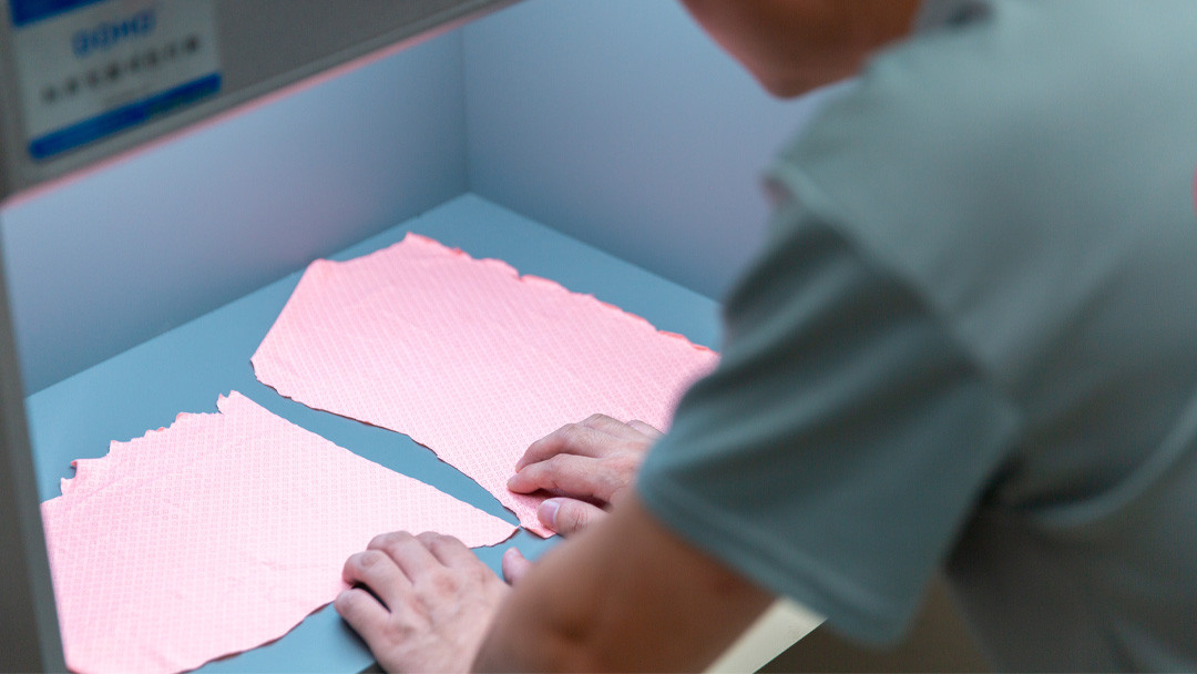QC inspector evaluating pink activewear fabric color matching inside a controlled D65 light box cabinet