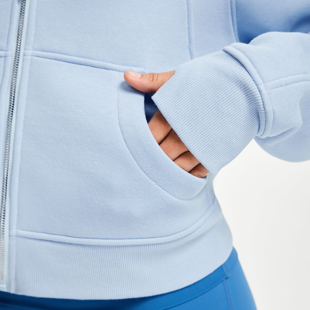 Close-up of a hand resting inside the split front pocket of a light blue fleece lined hoodie.