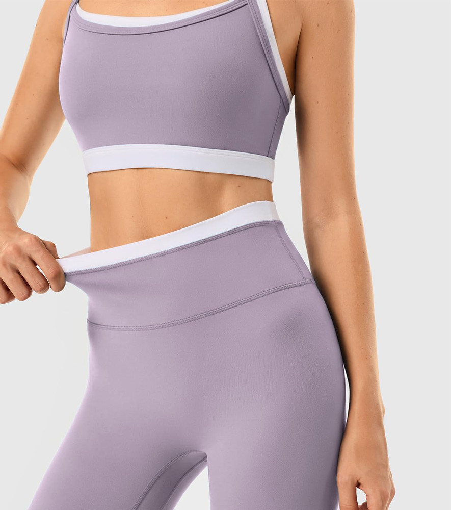 Close-up demonstrating the elasticity of the contrast color waistband on purple activewear leggings.