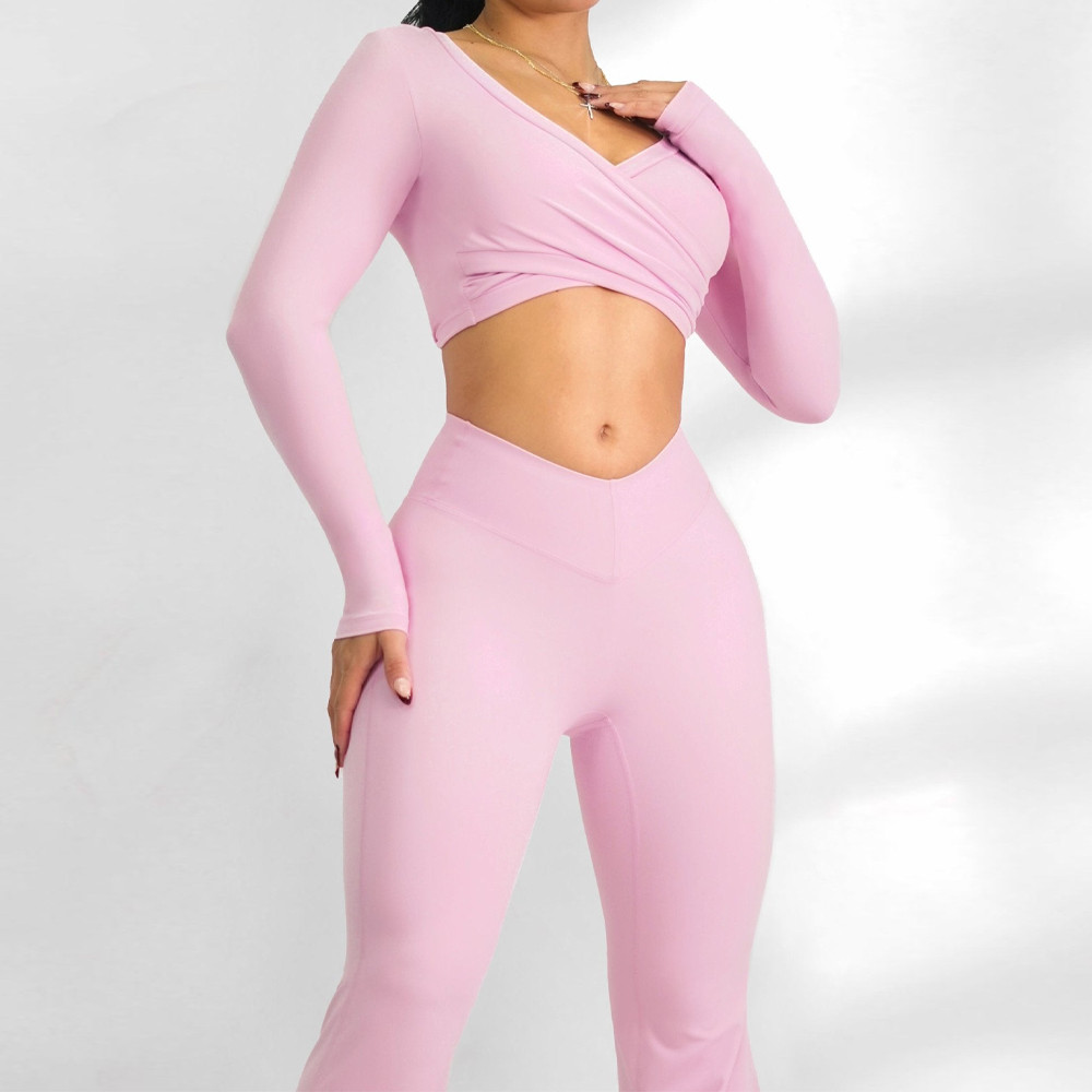 Close-up front view highlighting the overlapping cross front V-neckline of a light pink long sleeve activewear top.