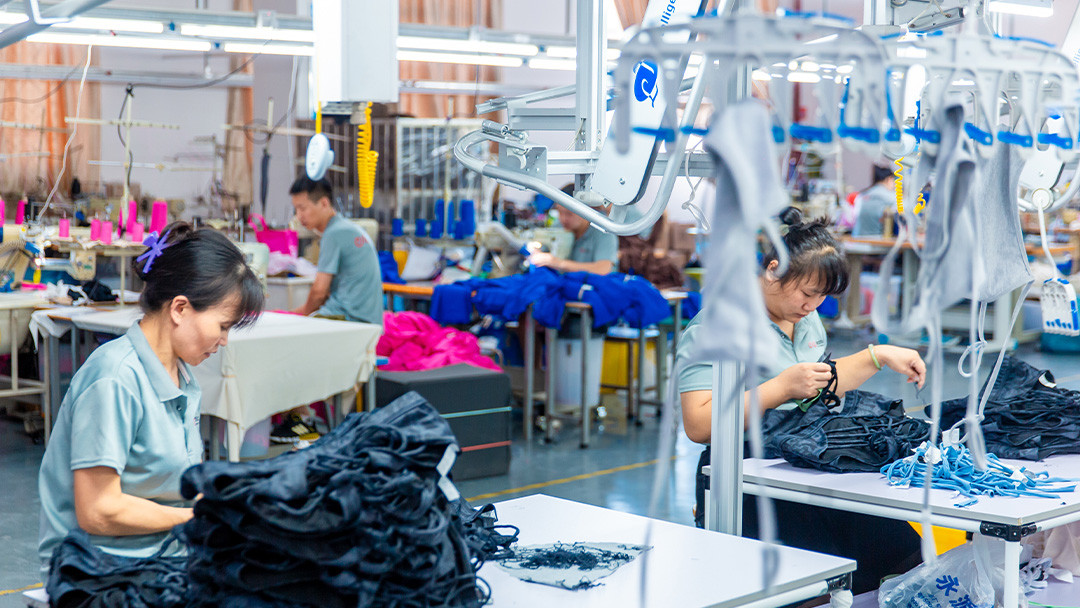 Skilled factory workers operating industrial sewing machines to ensure durable activewear construction.