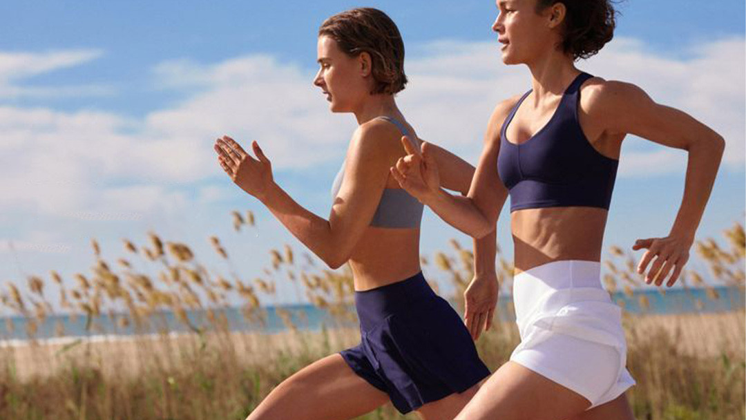 Women running outdoors in sports bras and performance running shorts