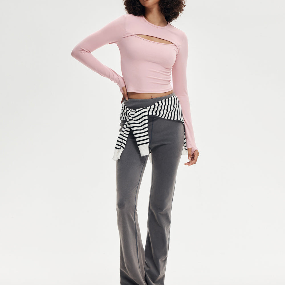 Front view of pink asymmetric cutout cropped long sleeve yoga top on model