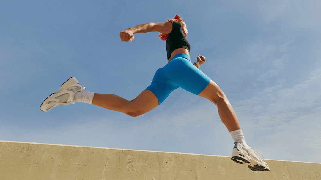 Woman running in fitted activewear shorts during a high-stretch movement