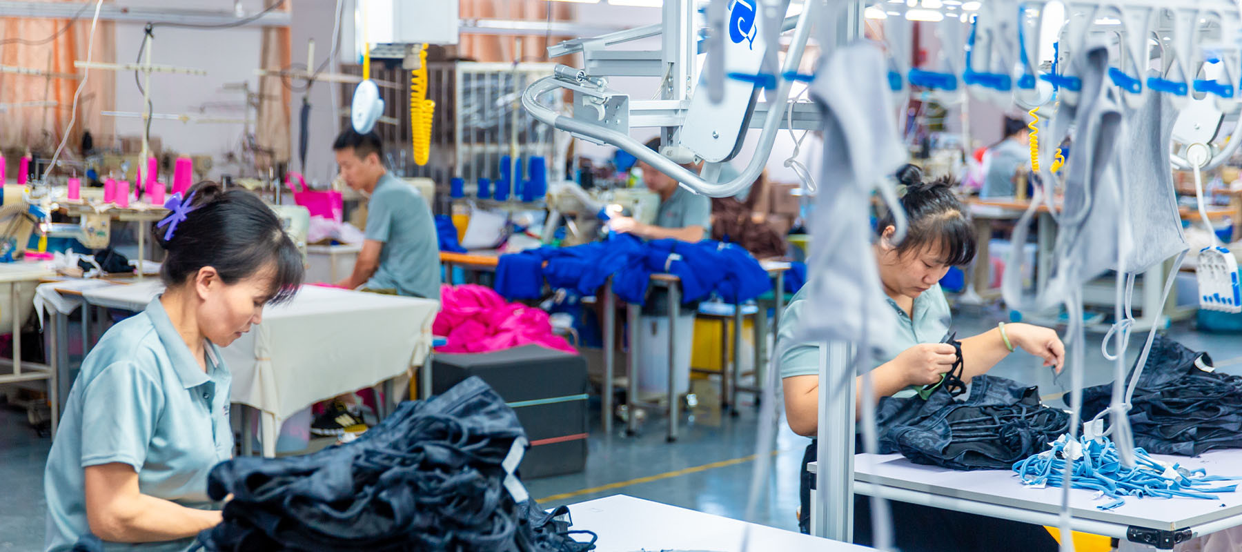Worker handling dark activewear garments on a factory production line