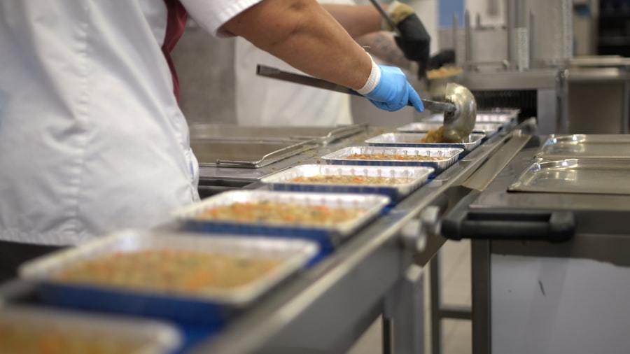 Worker filling food trays on a conveyor belt