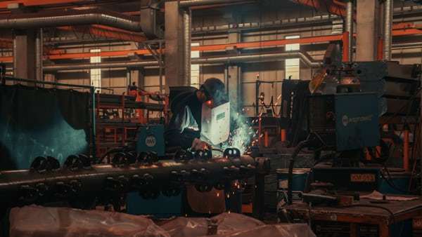 Factory worker operating CNC machine for serrated pulley production