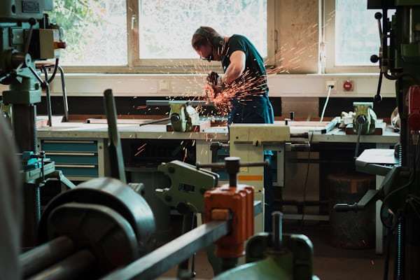 Industrial worker using angle grinder in manufacturing workshop