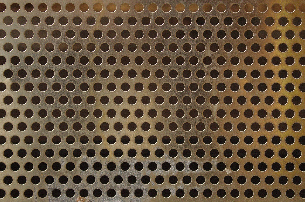 Close-up of aluminized silicon perforated steel sheet with round punched holes in a regular staggered pattern