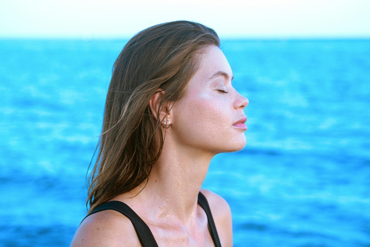 Person sitting peacefully on a beach breathing in fresh ocean air, calm and present