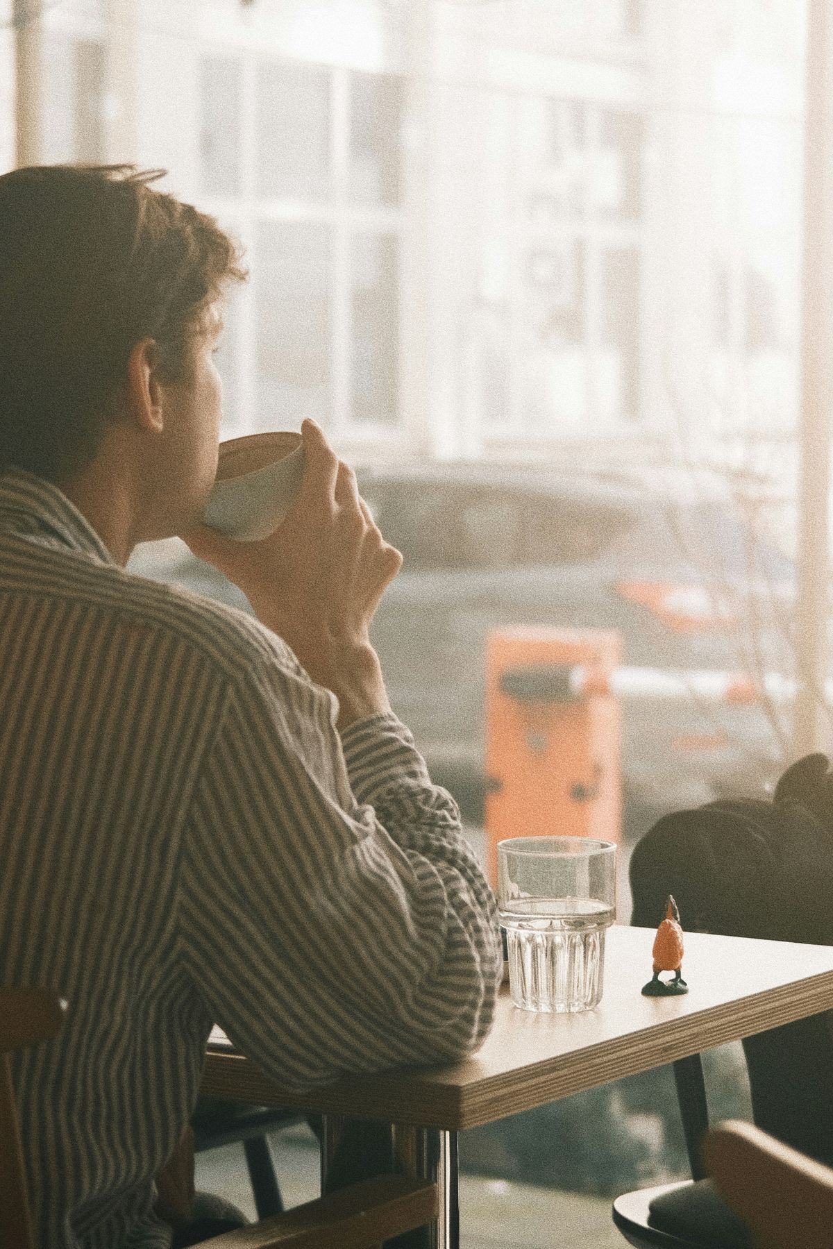 Man with warm drink by the window bathed in soft morning light