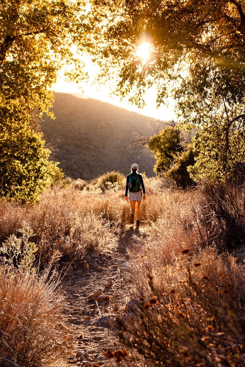 Woman walking along a dirt path through a forest, surrounded by nature