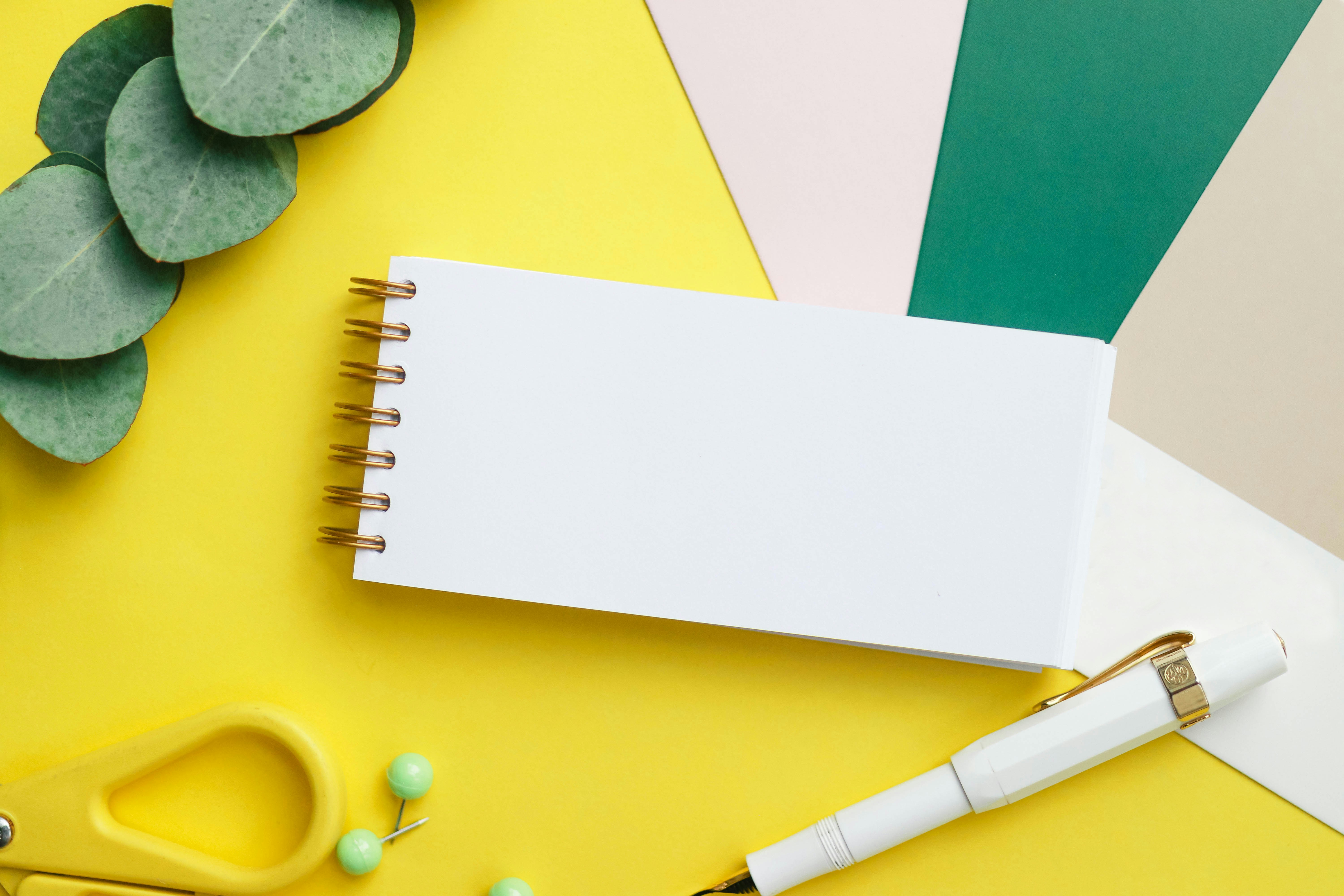 A flat lay photo of a custom coil notebook styled with pens and accessories for social media