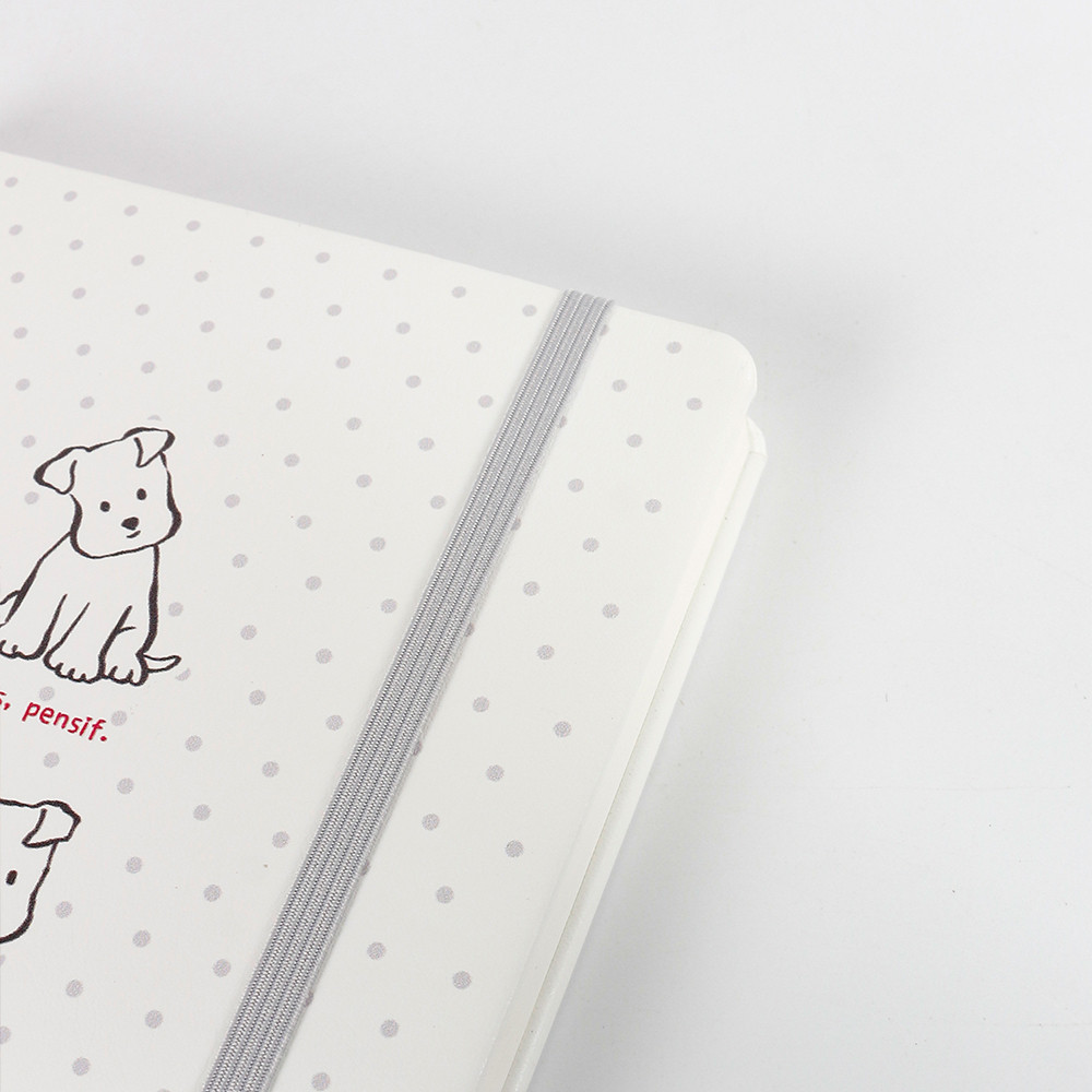 Close-up of the A5 MINI hardcover puppy notebook showing spotted dog, golden retriever and west highland illustrations with a light blue elastic closure strap.