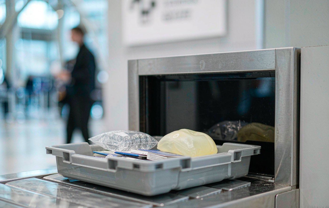 A soft squishy toy in an airport security tray entering an X-ray scanner