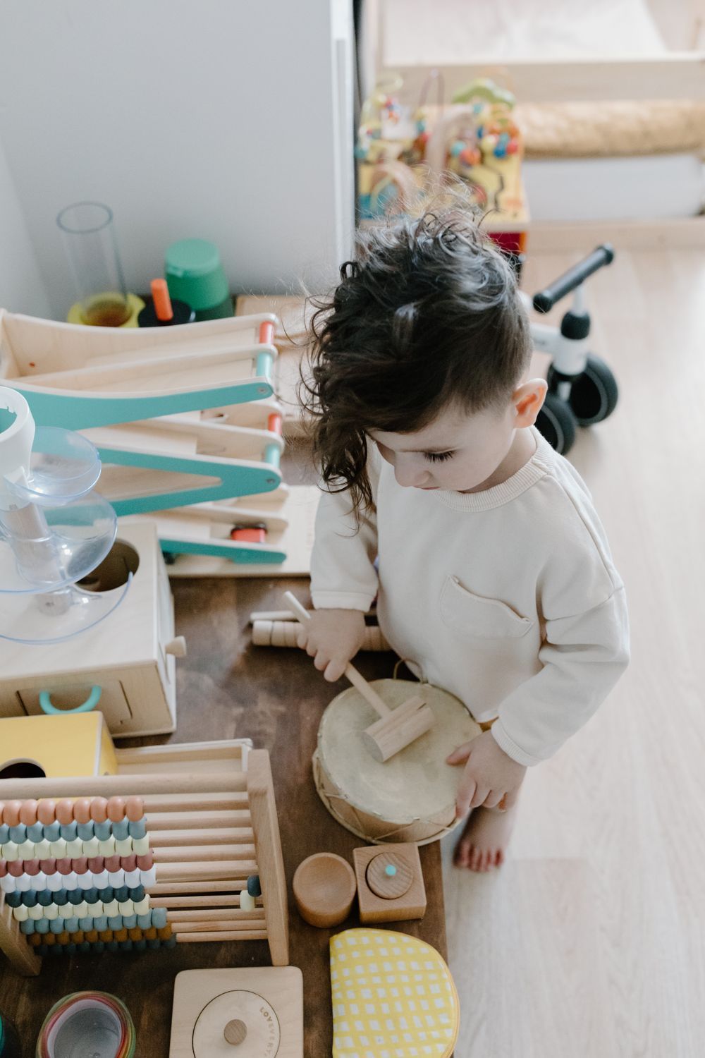 A toddler standing and playing with wooden toys