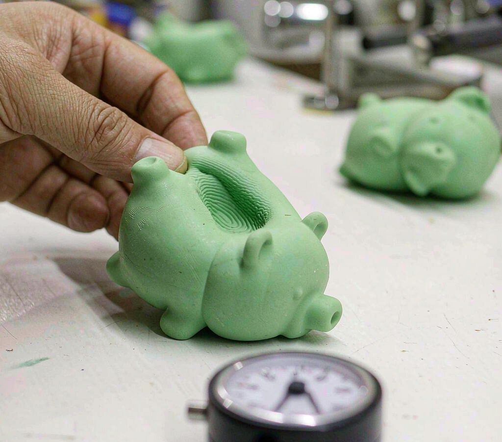 A quality control rebound test: a fingerprint dent slowly recovering on a pastel green squishy toy