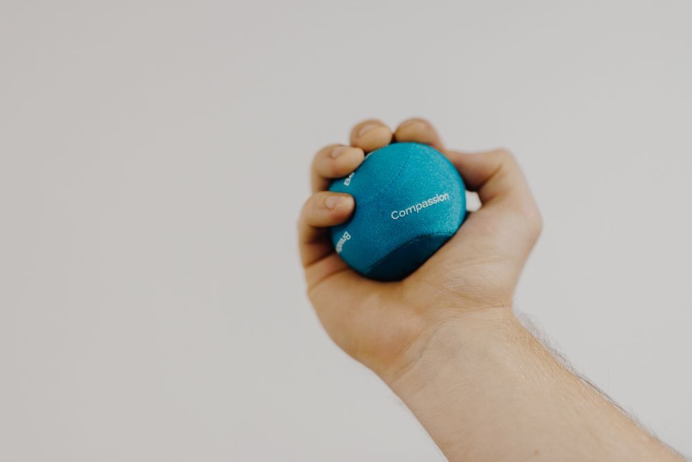 A hand squeezing a textured decompression stress ball