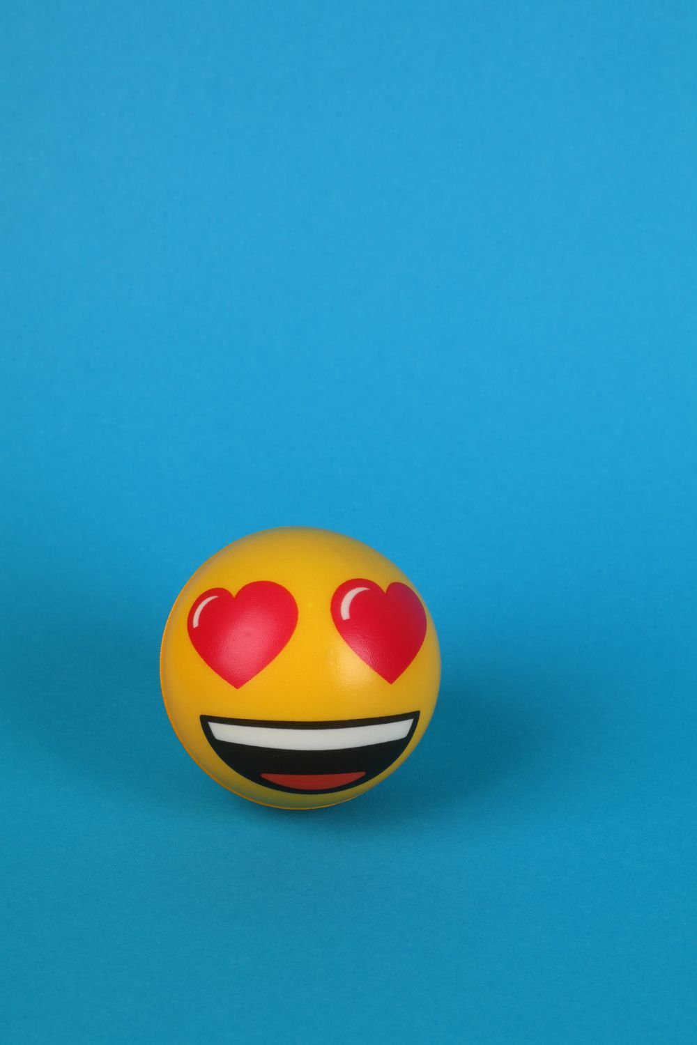 A yellow smiley-face stress ball on a blue background