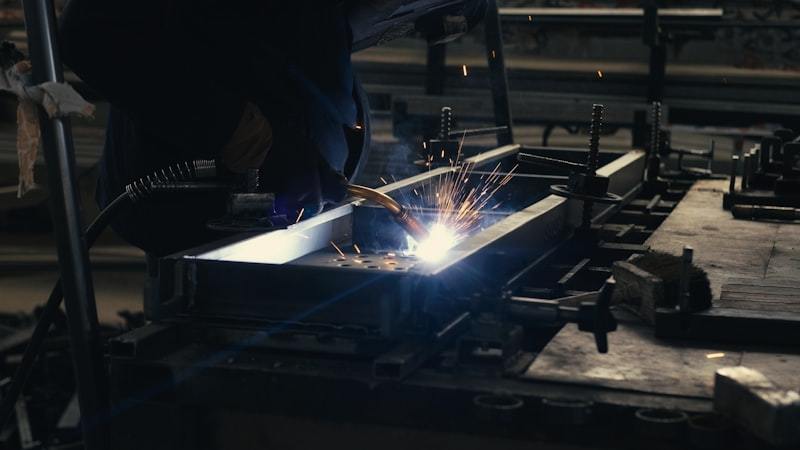 Welder working on metal piece in factory workshop