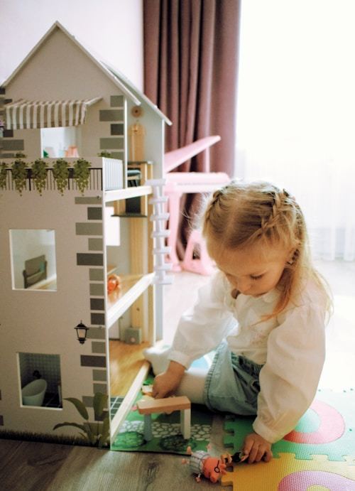 A little girl discovering the joy of dollhouse play, perfect for birthday surprises