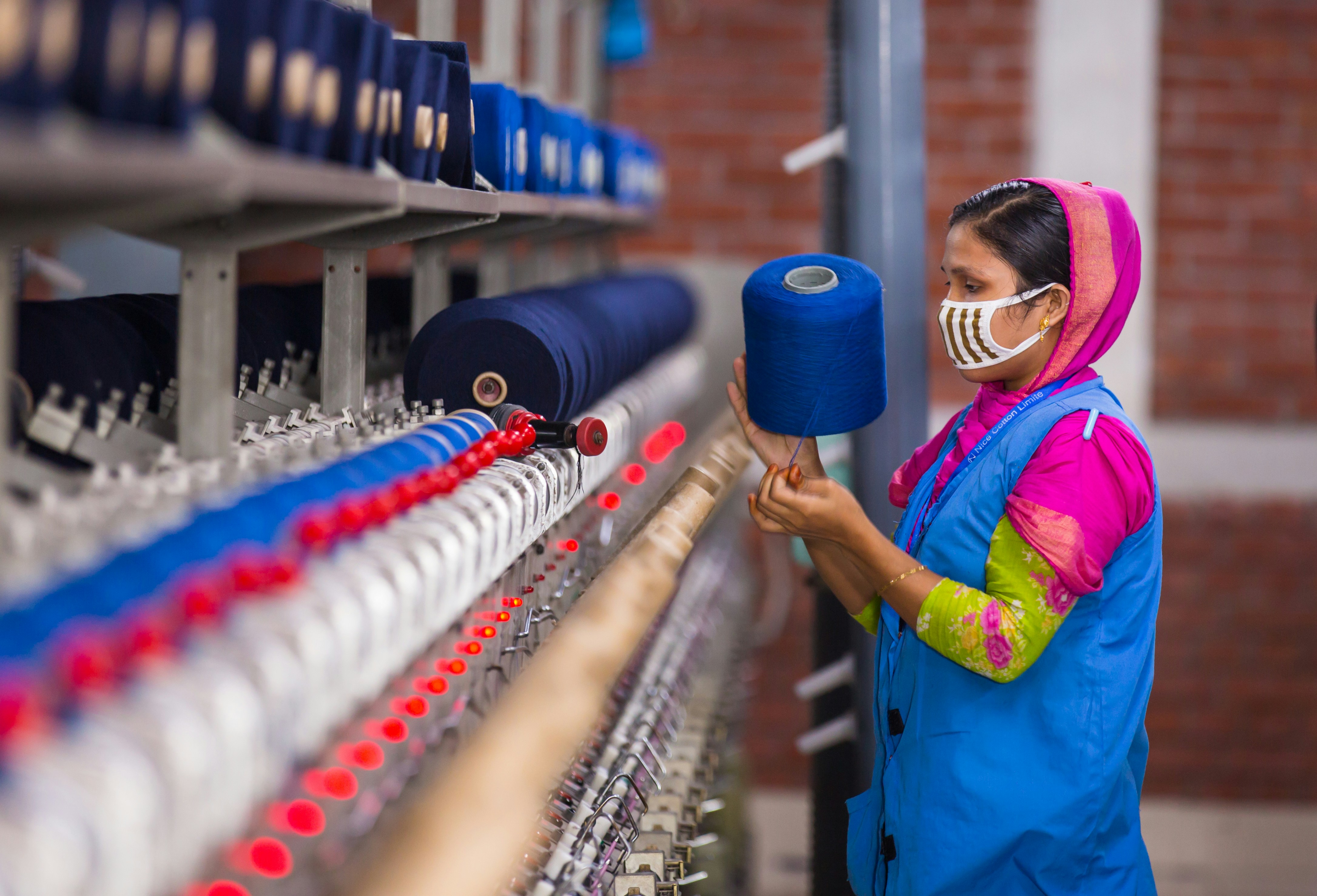 A quality control inspector examining yoga fabric with a magnifying glass in a factory setting
