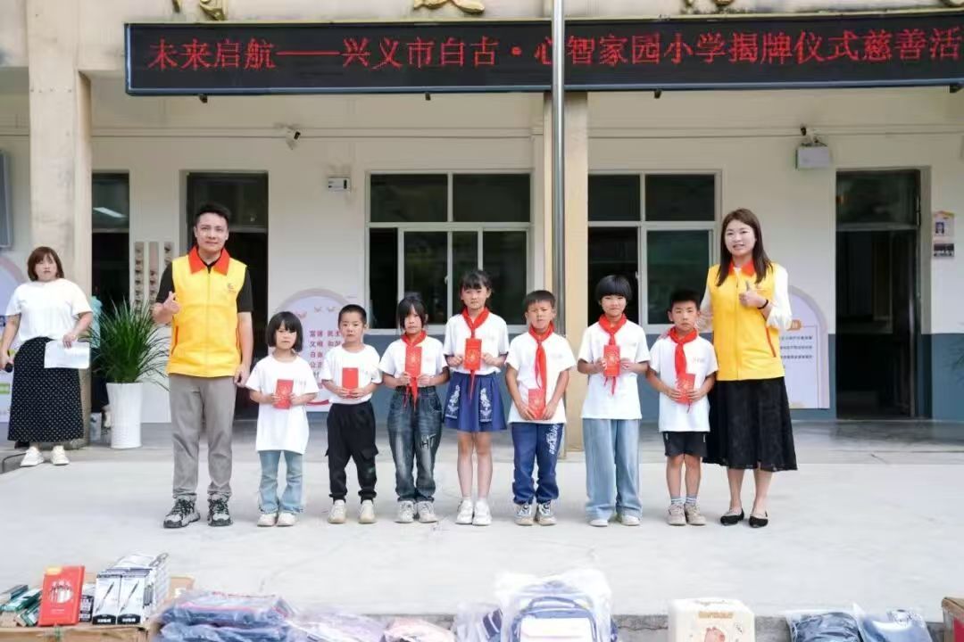 easemotion team at the "Future Sailing" charity unveiling ceremony at Xingyi Baigu Wisdom Home Primary School, distributing red envelopes to students