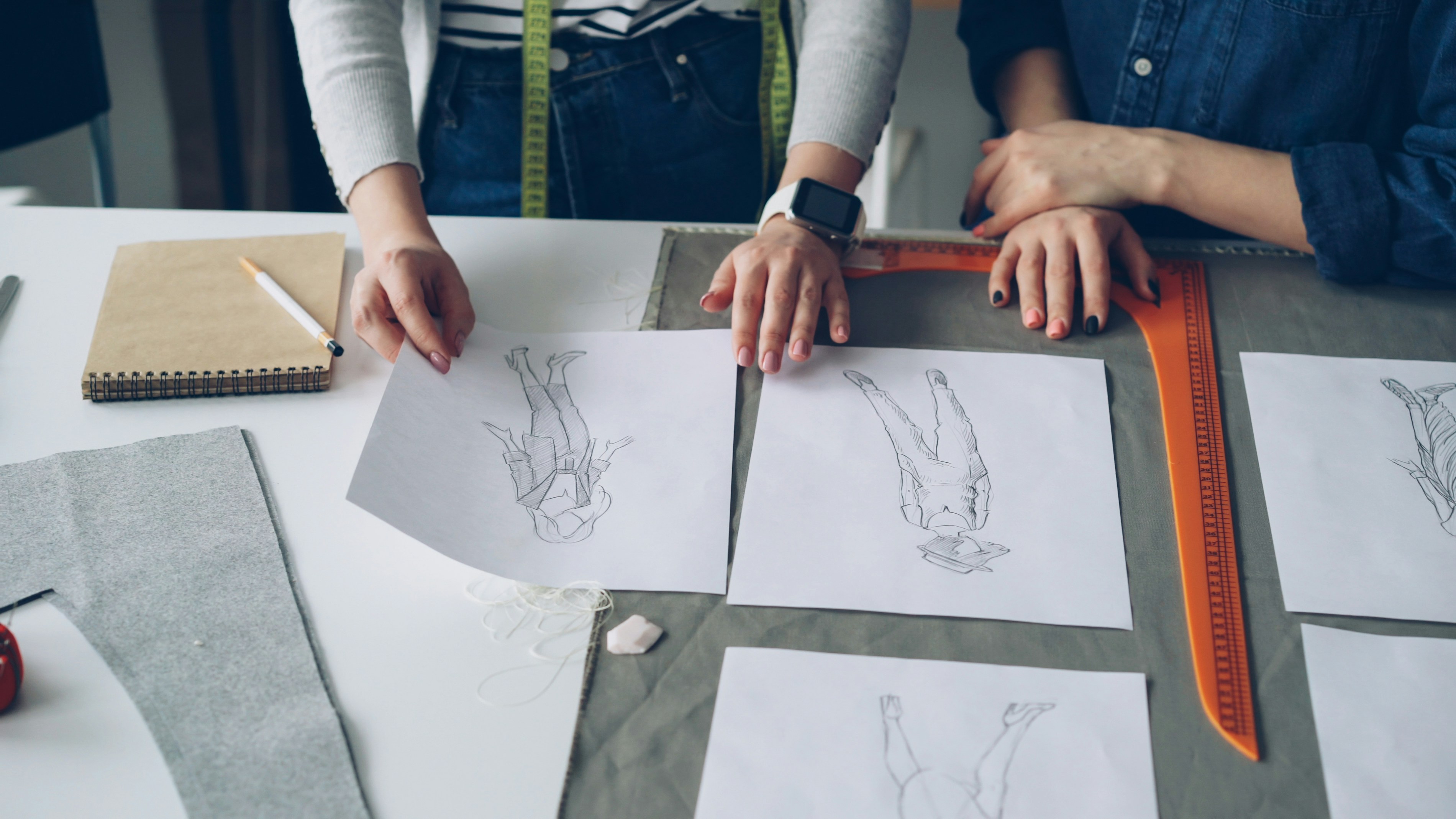 A designer and a pattern maker collaborating over sketches and fabric swatches for a new yoga line