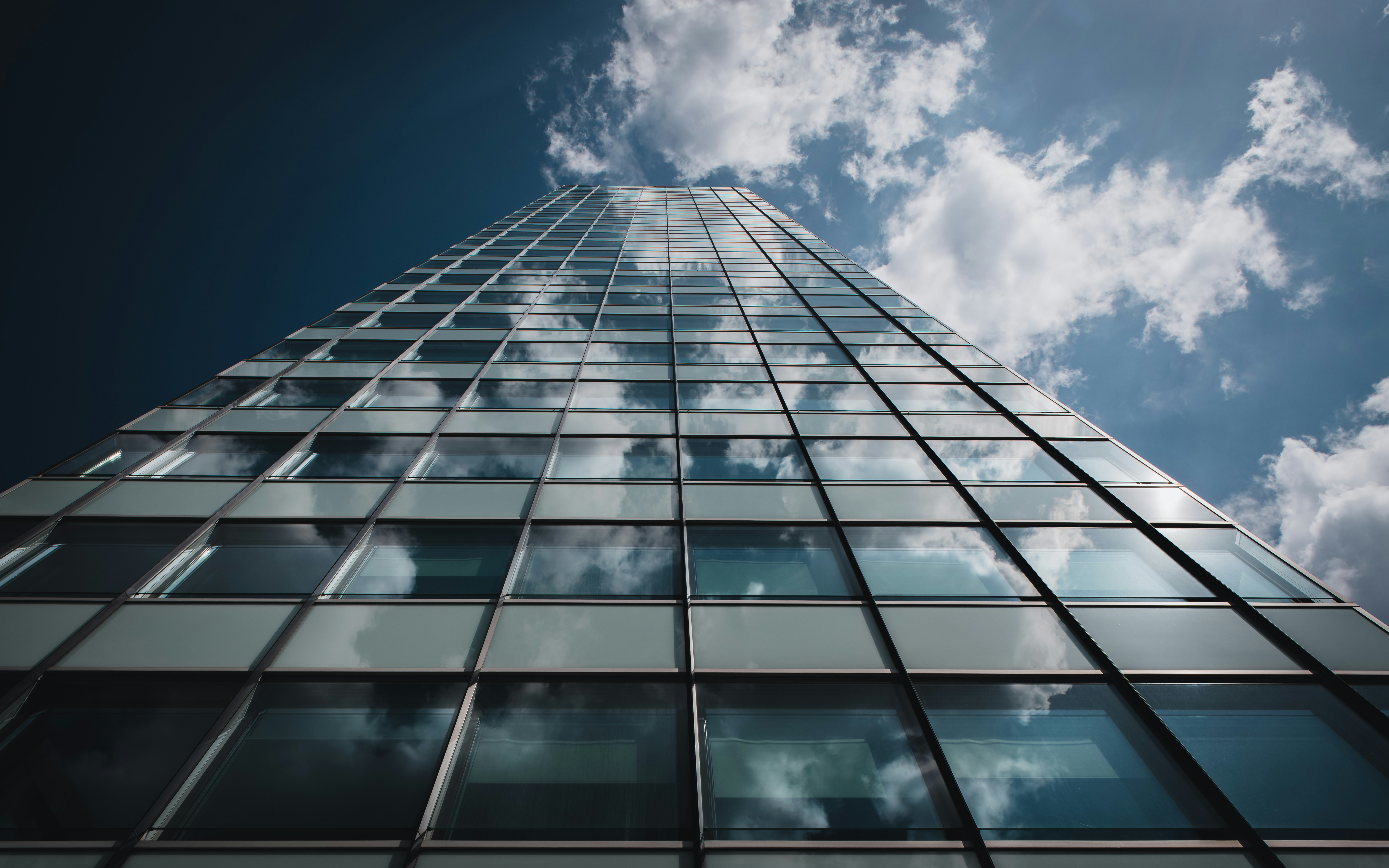 Sleek glass facade of a modern high-rise with a curtain wall system A modern skyscraper featuring a glass curtain wall reflecting the sky.