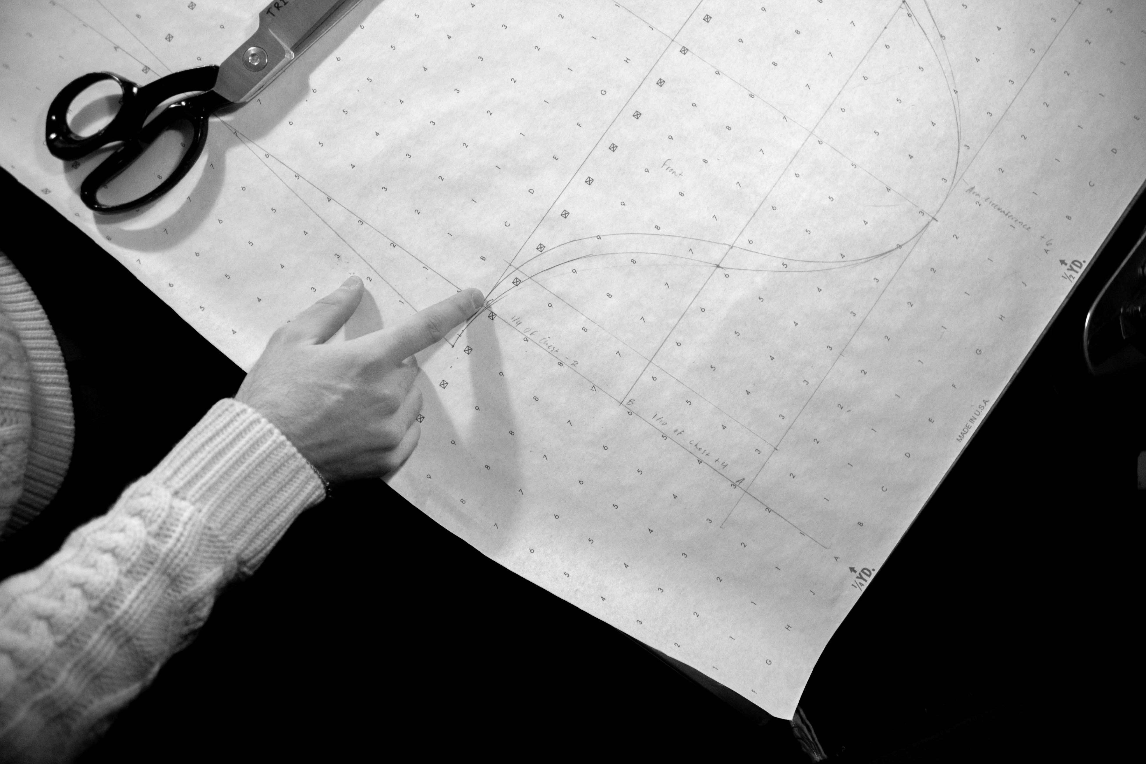 Close-up of a hand pointing to a specific detail on a complex curtain wall shop drawing.