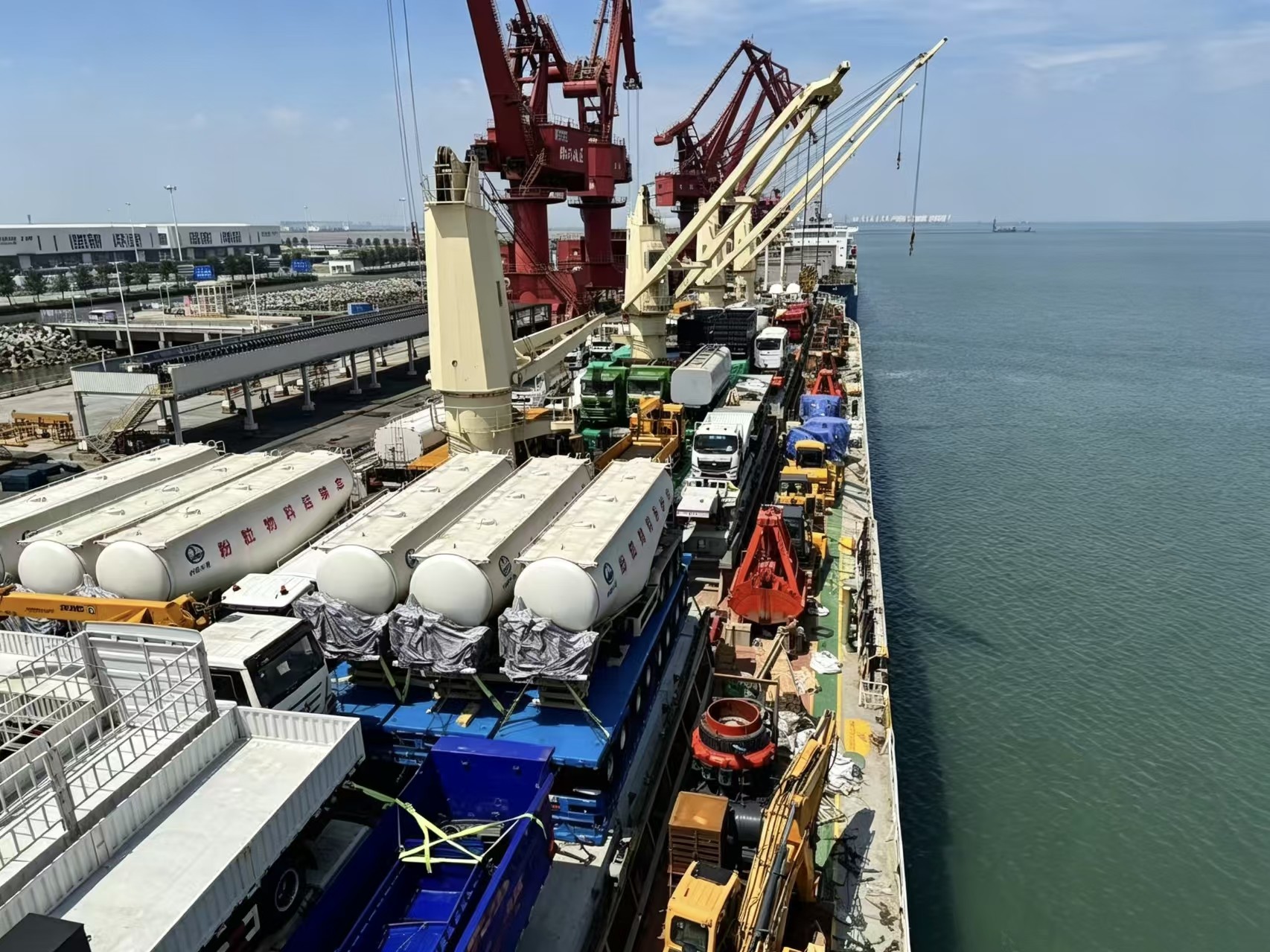 Multi-purpose heavy-lift vessel with deck cranes in harbour