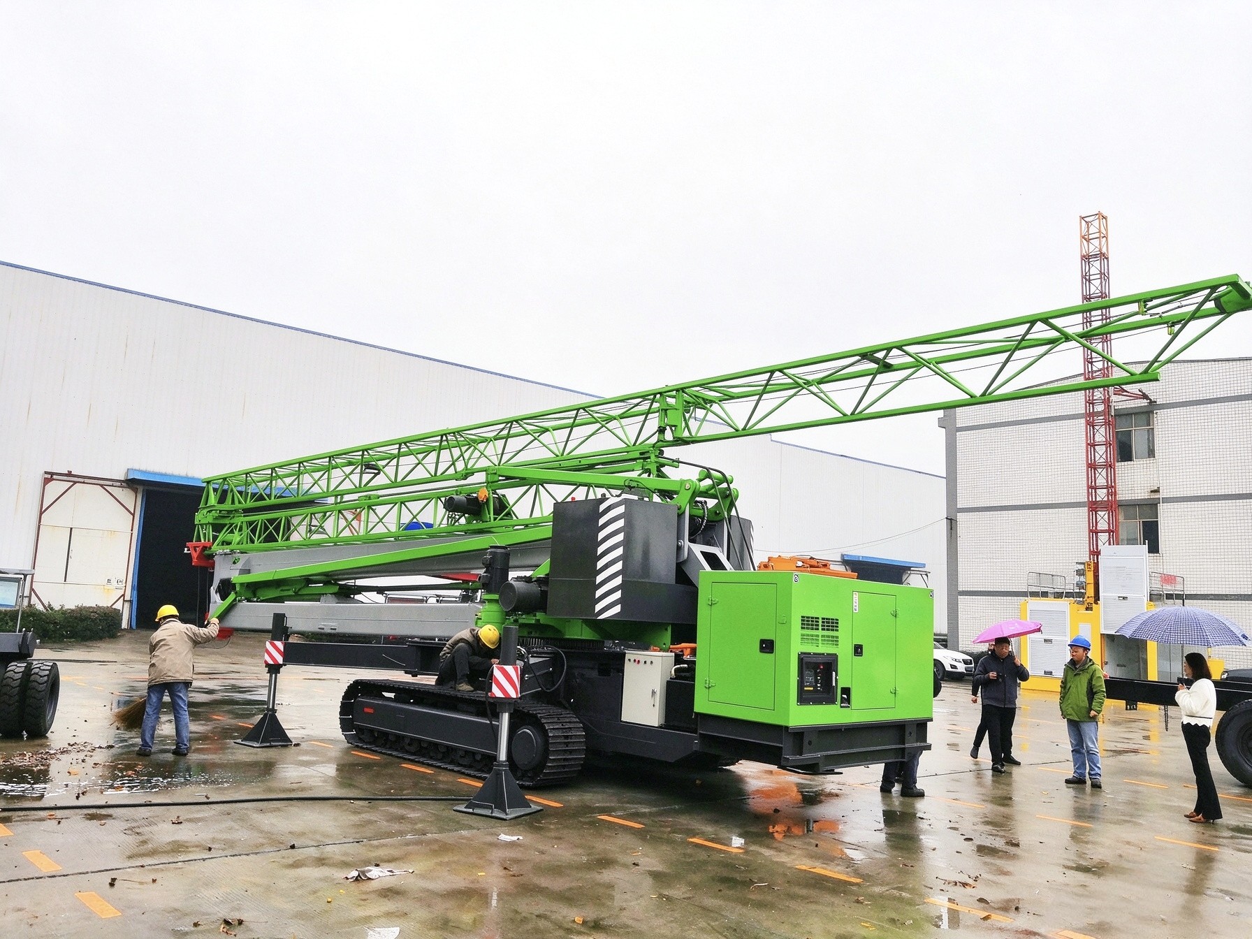 Engineers in hard hats inspecting heavy mining excavator at factory workshop